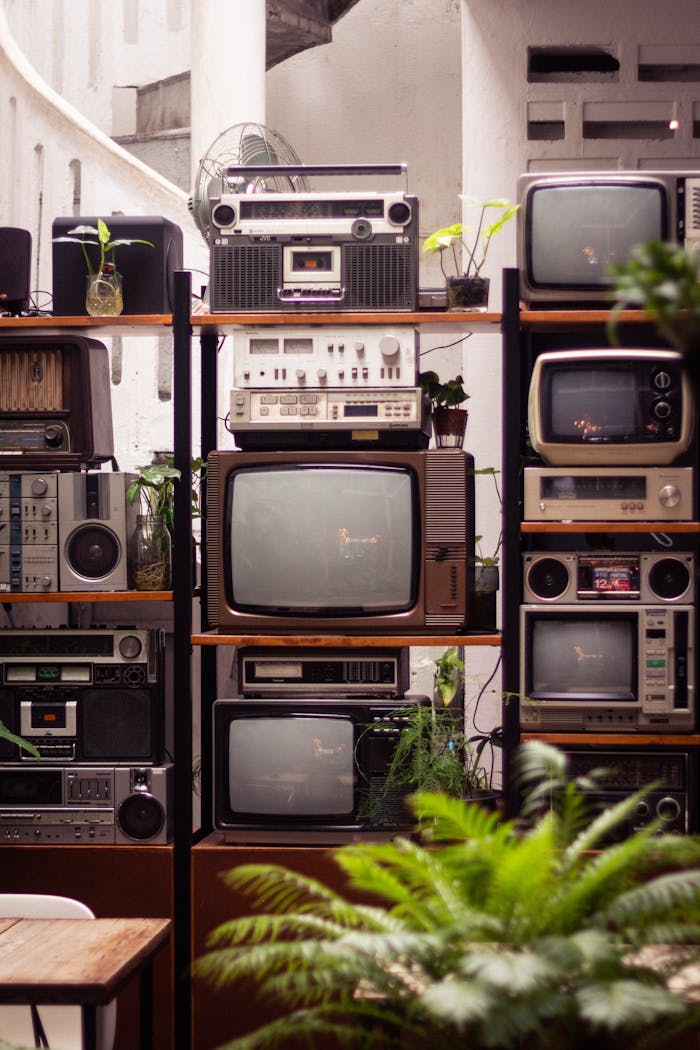 An array of vintage audio and television equipment artfully displayed with lush green plants in Kuala Lumpur.